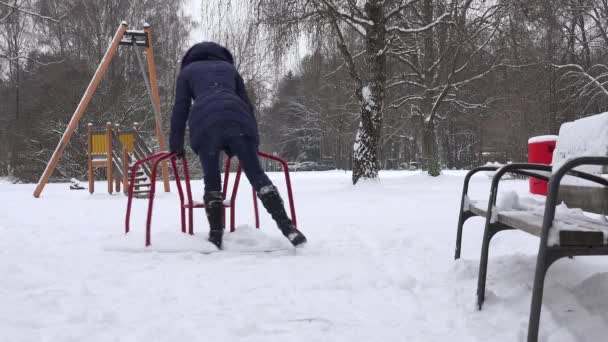 Młoda kobieta swing w plac zabaw dla dzieci w czasie zimy. 4k — Wideo stockowe