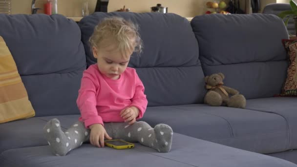 Niña utilizar el teléfono móvil inteligente sentarse en la habitación del sofá. Nueva tecnología. 4K — Vídeos de Stock