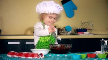 Şef şapkalı kız ciddi güzel çocuk un ekleyip hamur kaşık ile karıştırın