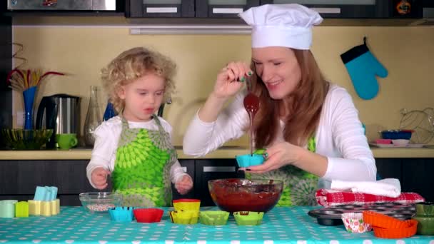 Mulher bonita e filha adorável estão sorrindo ao preencher casos de muffin — Vídeo de Stock