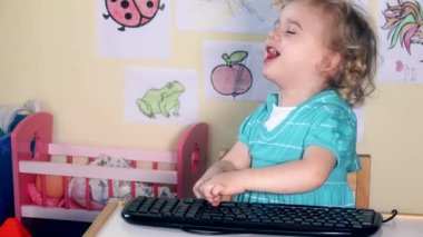 Onun küçük masa üstünde bilgisayar klavye ile oynarken duygusal yürümeye başlayan çocuk kız