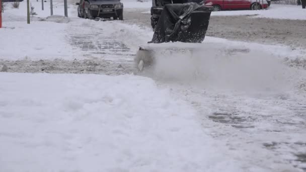 Worker with snow blower clean snow from footpath on snowy street at winter. 4K — Stock Video