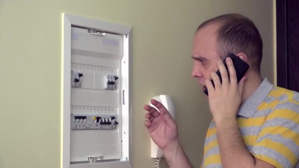 Мужчина консультируется по телефону по поводу неисправности электропроводки в собственной комнате. 4K — стоковое видео
