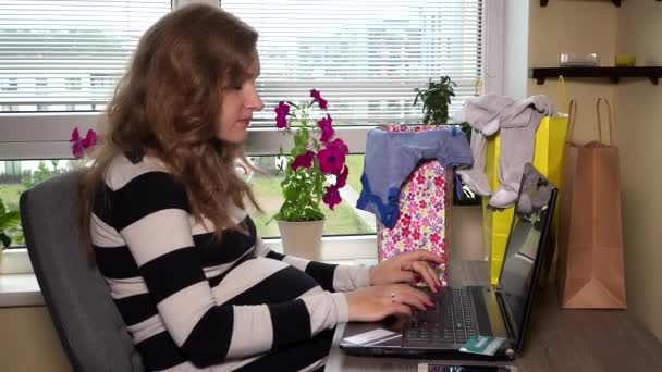 Femme enceinte avec carte de crédit acheter des vêtements de bébé sur Internet concept — Video