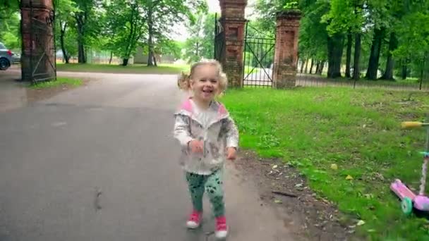 Riendo chica traviesa corriendo en Park Road. Lindo niño pequeño diviértete al aire libre — Vídeos de Stock