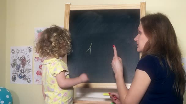 Lehrerin schreibt Zahlen auf Kreidetafel für kleines Mädchen — Stockvideo