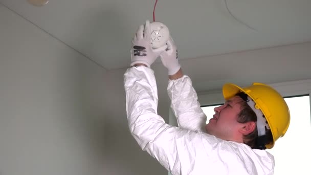 Молодой электрик устанавливает датчик пожарного дыма — стоковое видео