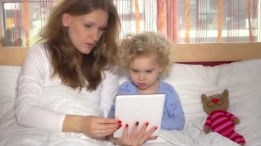 tablet bilgisayarda oyun oynayan küçük sevimli kız güzel annesiyle