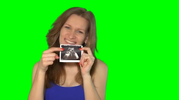 Těhotná žena drží sonogram při pohledu na fotoaparát a usmívá se. — Stock video