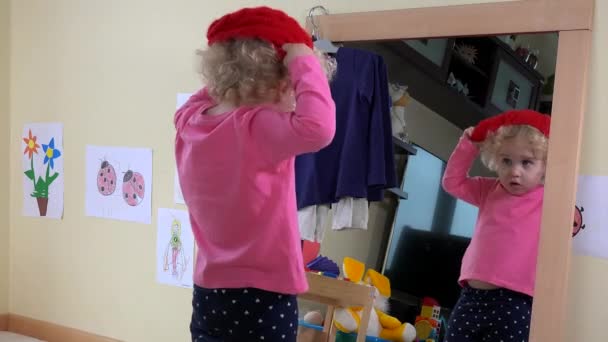 Roztomilá dívka opatření klobouky před zrcadlem doma — Stock video