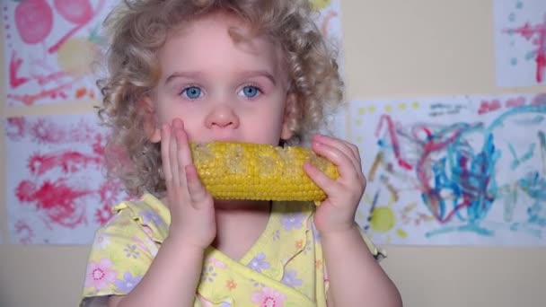 Маленькая симпатичная девочка ест вареную кукурузу. flycam shot — стоковое видео