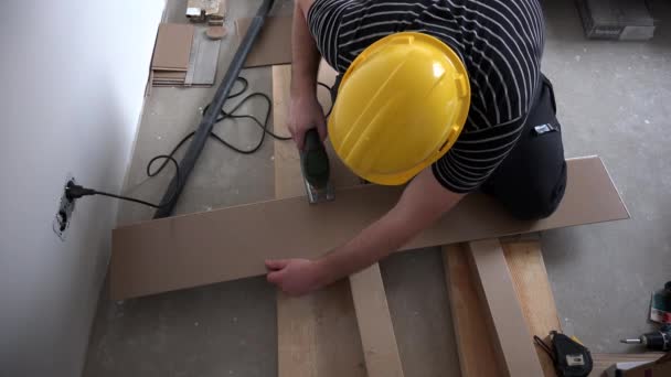 Man working with jigsaw and wooden laminate floor panels — Stock Video