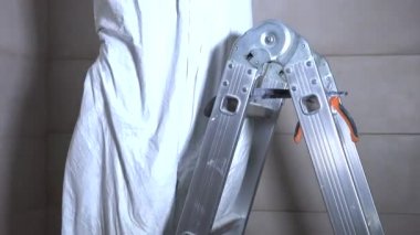 Çalışan adam merdivene tırmanmak ve aydınlatma için kablo yalıtım kaldırmak