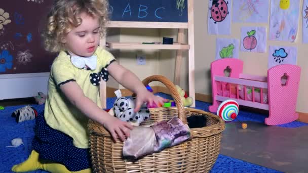 Niña pequeña poner juguetes a la cesta de mimbre. Habitación desordenada en casa — Vídeo de stock