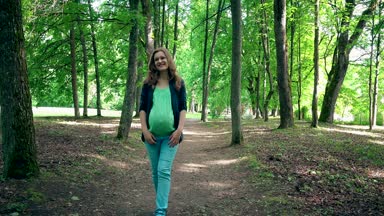 Genç hamile kadın parkta tek başına yürüyor ve karnının vuruş