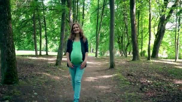 Unga gravid kvinna vandrar ensam i parken och smeker sin buken — Stockvideo