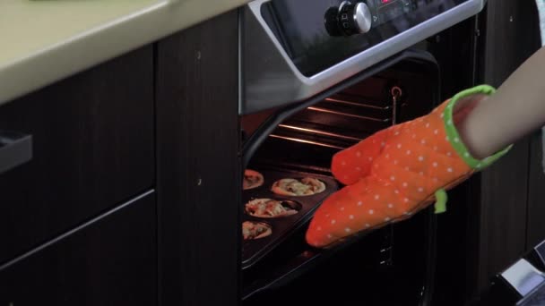 Господиня рука з теплозахисною рукавичкою відкриває двері духовки і бере торти з м'ясом — стокове відео