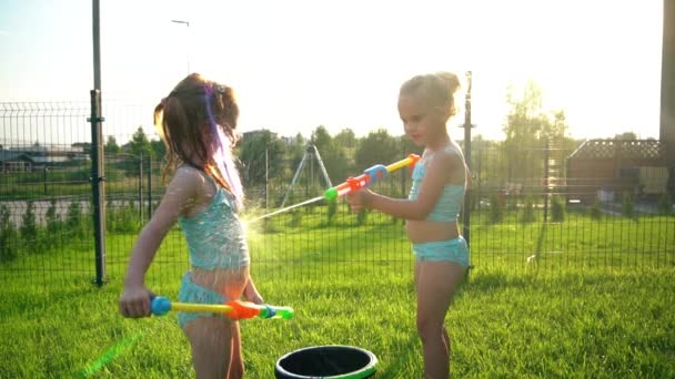 Stoute meisjes in zwempakken die elkaar besprenkelen met waterpistolen. Langzame beweging. — Stockvideo
