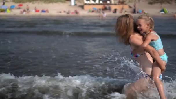 Crazy mother woman running through sea waves carrying little daughter girl — ストック動画