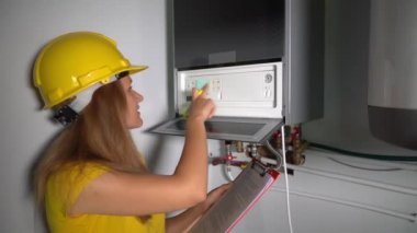 Technician girl inspect maintenance gas boiler heating system at private house