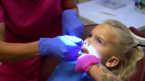 Tandarts met assistent met getatoeëerde handen repareren kleine meisje kind tand — Stockvideo