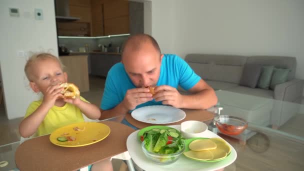 Man and boy with hamburgers - teaching unhealthy diet by example concept — ストック動画