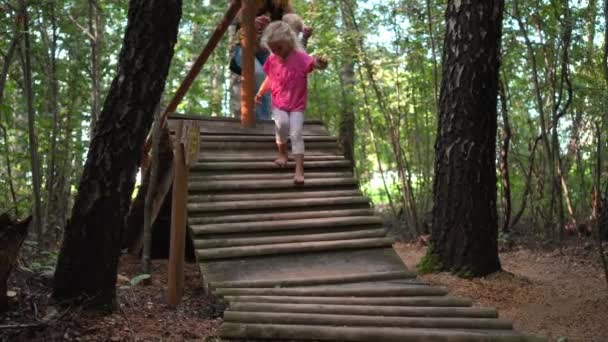 Les gens marchent à travers le pont en bois bâtons. Femme avec enfants. Massage des pieds nus . — Video