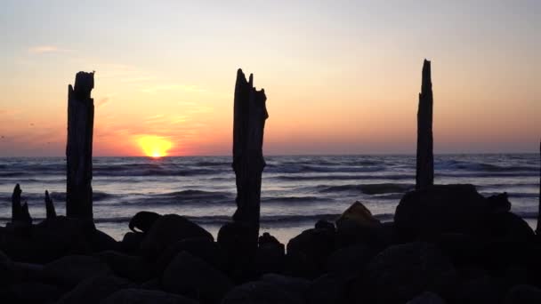 Vieille jetée abandonnée ou pierres de pont et grumes et coucher de soleil orange sur le fond . — Video