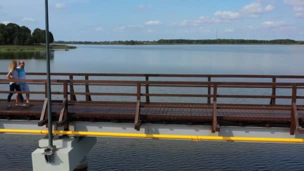 Mujer cariñosa y hombre caminando por la pasarela sobre el lago. Familia joven feliz — Vídeos de Stock