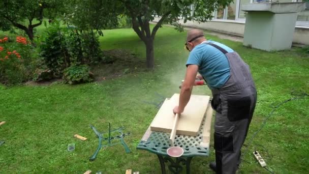 Arbetaren polerar brädorna med en polermaskin. Arbete med rengöring av trä — Stockvideo