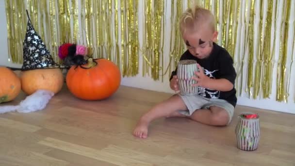 Menino com maquiagem em um traje de esqueleto brincando com doces doces — Vídeo de Stock