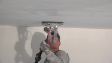 Tavanı elektrikli öğütücüyle cilalayan adam. Tozlu inşaat işçisi