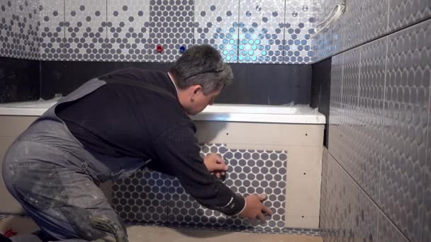 Umiejętny człowiek układał kafelki po stronie wanny w łazience — Wideo stockowe