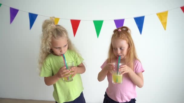 Vilaines filles faisant des bulles dans des verres de jus d'orange avec de la paille — Video