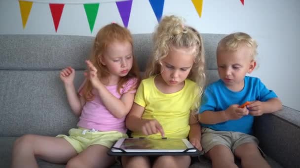 Enfants partageant une tablette assis sur le canapé. Frustré rousse fille — Video