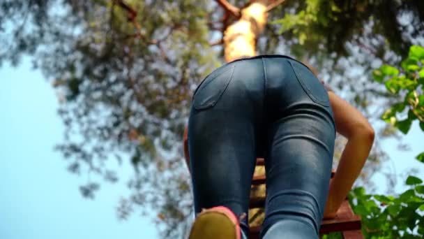 Woman climbing on high wooden ladder outdoor. Legs and ass visible — 图库视频影像