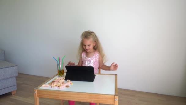 Aktív lány gyermek kapcsolja be a zenét a táblagépen, és táncolni a széken. Gimbal mozgás — Stock videók