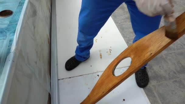 Painter is painting varnishing oiling wood boards in oak color with paint brush — Stock Video