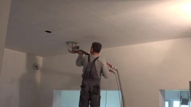 Zımpara kağıdı makinesiyle tavanı cilalayan tamirci.