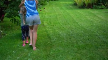 Anne ve küçük kızı akşam bahçesinde çim biçme makinesi itiyorlar.