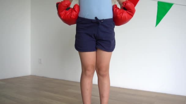 Schmollgesicht Kleinkind Mädchen mit Boxhandschuhen posiert und schaut in die Kamera. Zeitlupe — Stockvideo