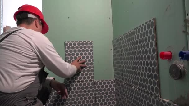 Obrero de la construcción con pared de azulejos de casco rojo con baldosas cerámicas — Vídeos de Stock