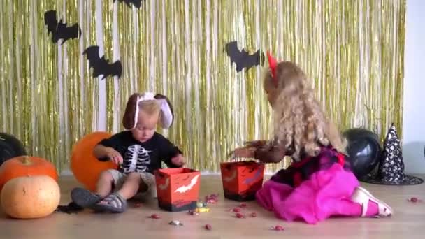 Little brother boy and blond sister girl pick sweets in halloween decorated room — Stock Video