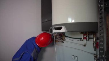 Profesyonel teknisyen sorun var mı diye gaz kazanını inceliyor. Erkek işçi.