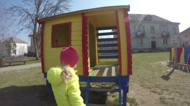 Nettes Mädchen betritt buntes Spielhaus. Weibliches Kind schaut durch Fenster — Stockvideo