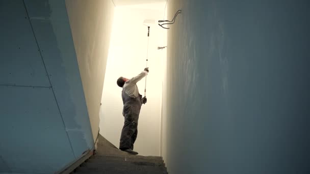 Peintre bricoleur plafond de peinture de couleur blanche avec rouleau bâton — Video