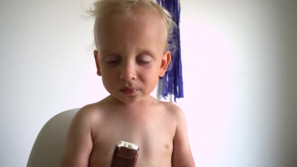 Niño hambriento comiendo helado en palo. Movimiento del cardán — Vídeos de Stock