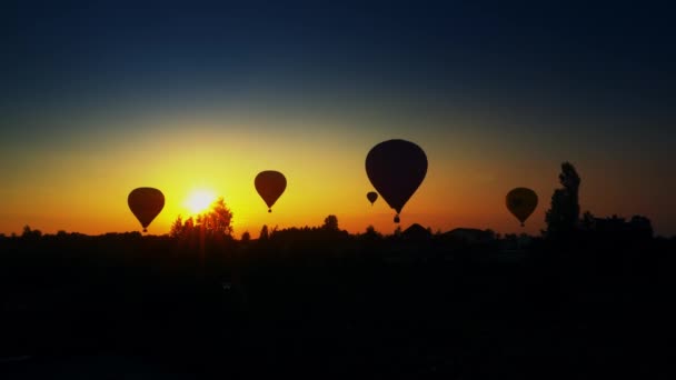 Hot air balloons landing in field over amazing sunset. Dramatic color grading — Stock Video