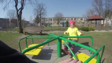 Baba eli şehir parkında salıncakta sallanan yaramaz küçük kızı döndürür.