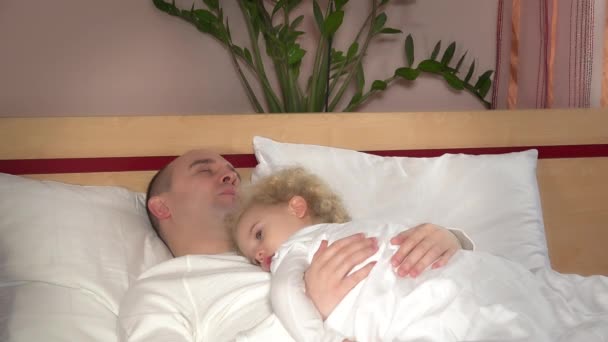 Linda niña hija acostada en dormir padre hombre pecho en la cama — Vídeos de Stock